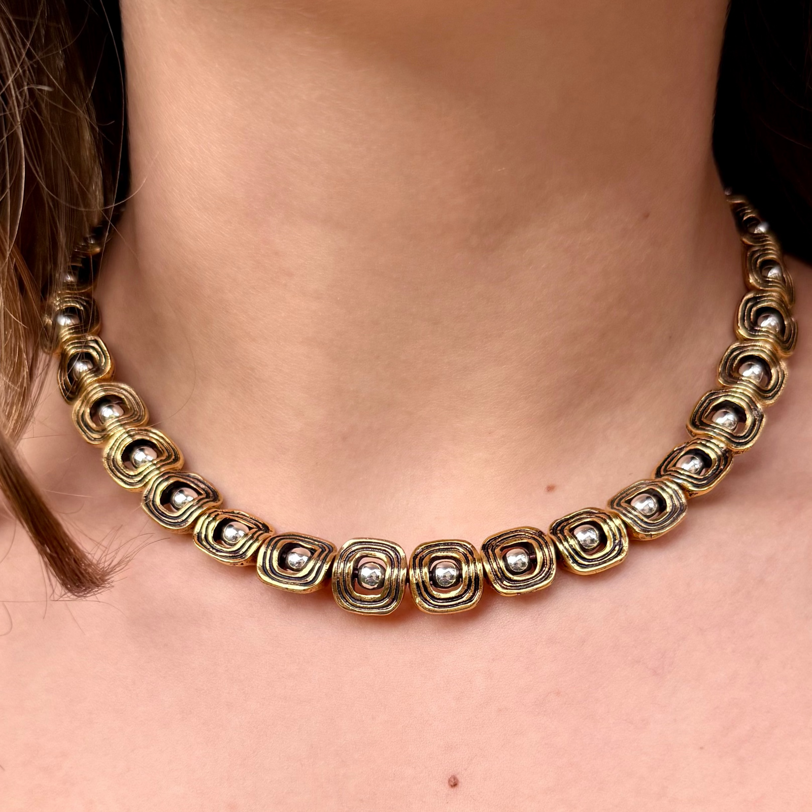 Gold necklace with silver beads worn by a person