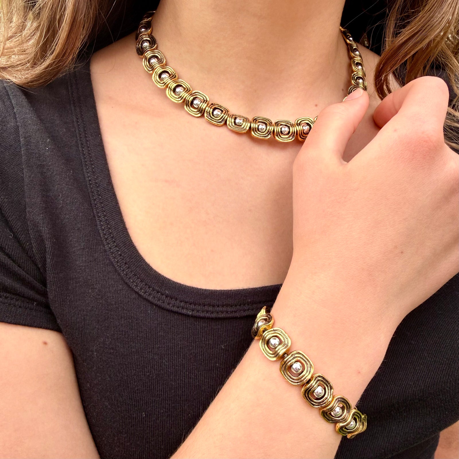 Gold bracelet with circular designs on a wrist against a black background