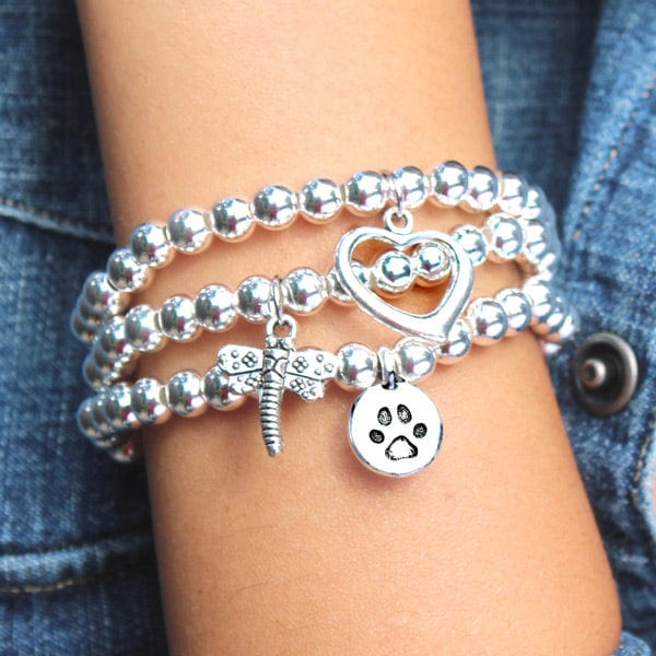 Silver bracelets stacked with dragonfly charm