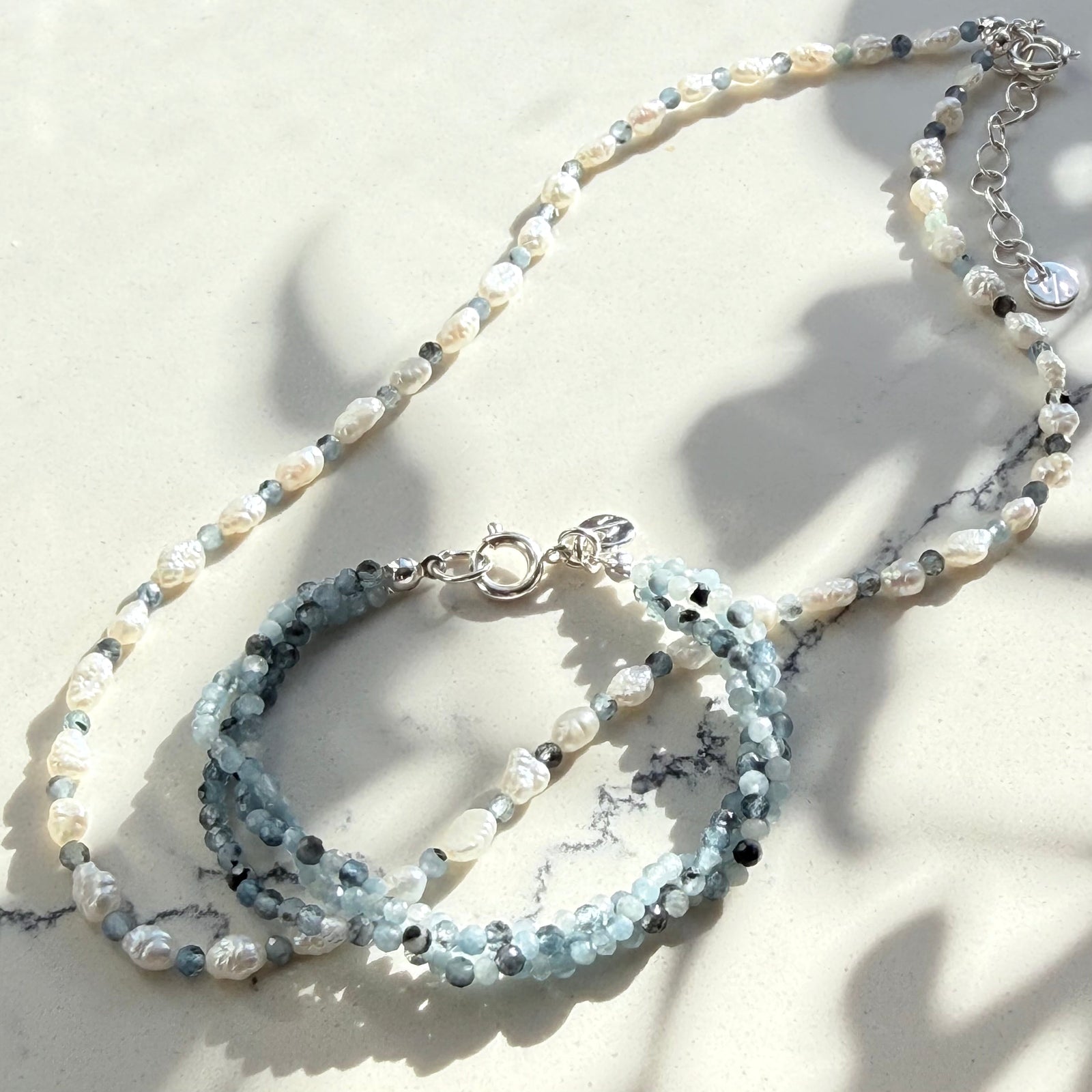 Necklace with multiple strands of pearls and gemstones on a light background