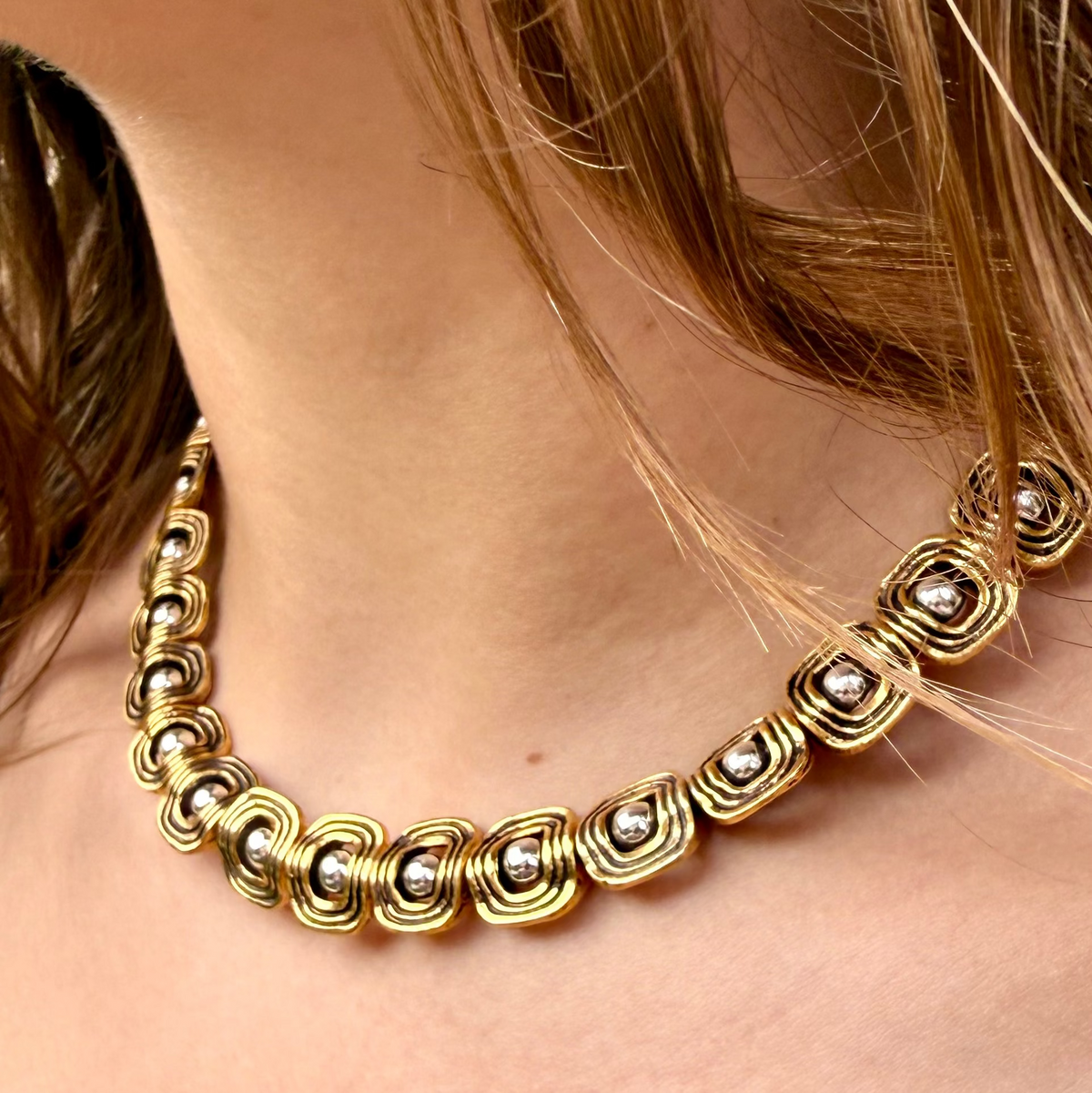 Gold necklace with silver beads worn by a person