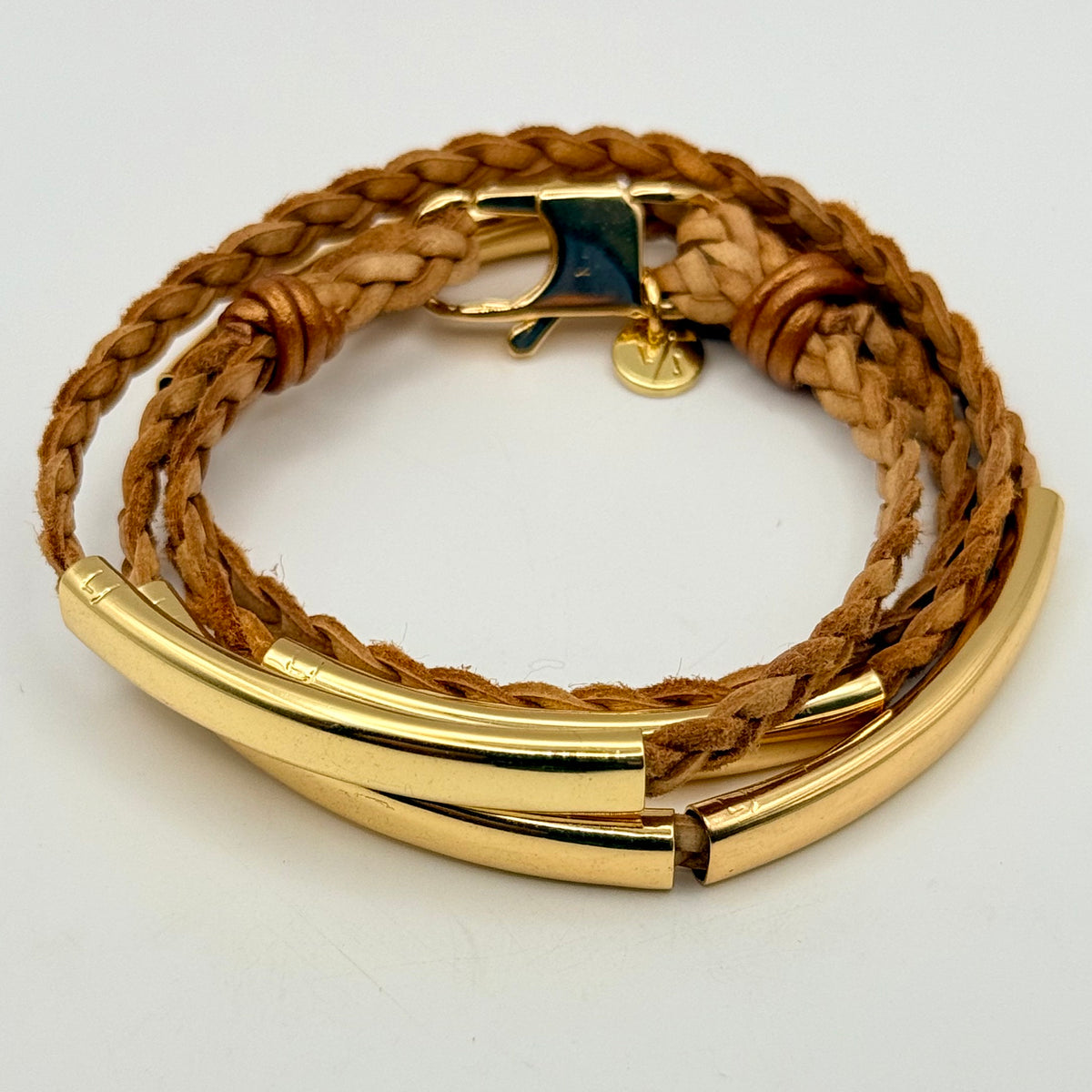 Brown braided leather bracelet with gold accents on a white background