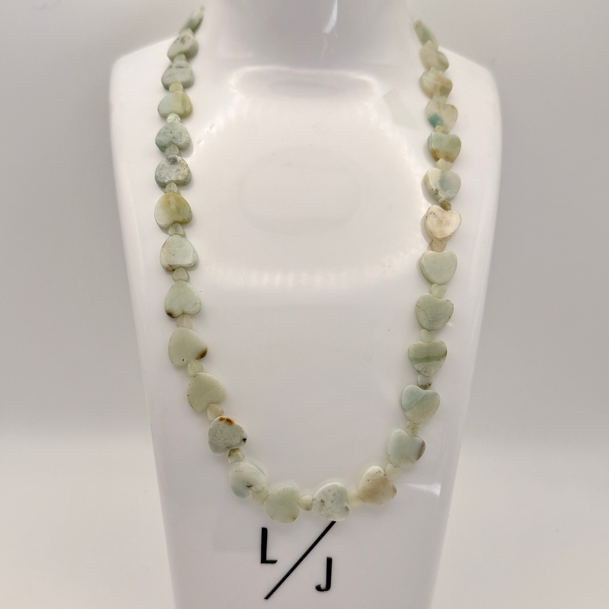 Adjustable 16 to 18 inch necklace with a mix of large and small light teal Amazonite heart-shaped gemstones and a silver clasp.