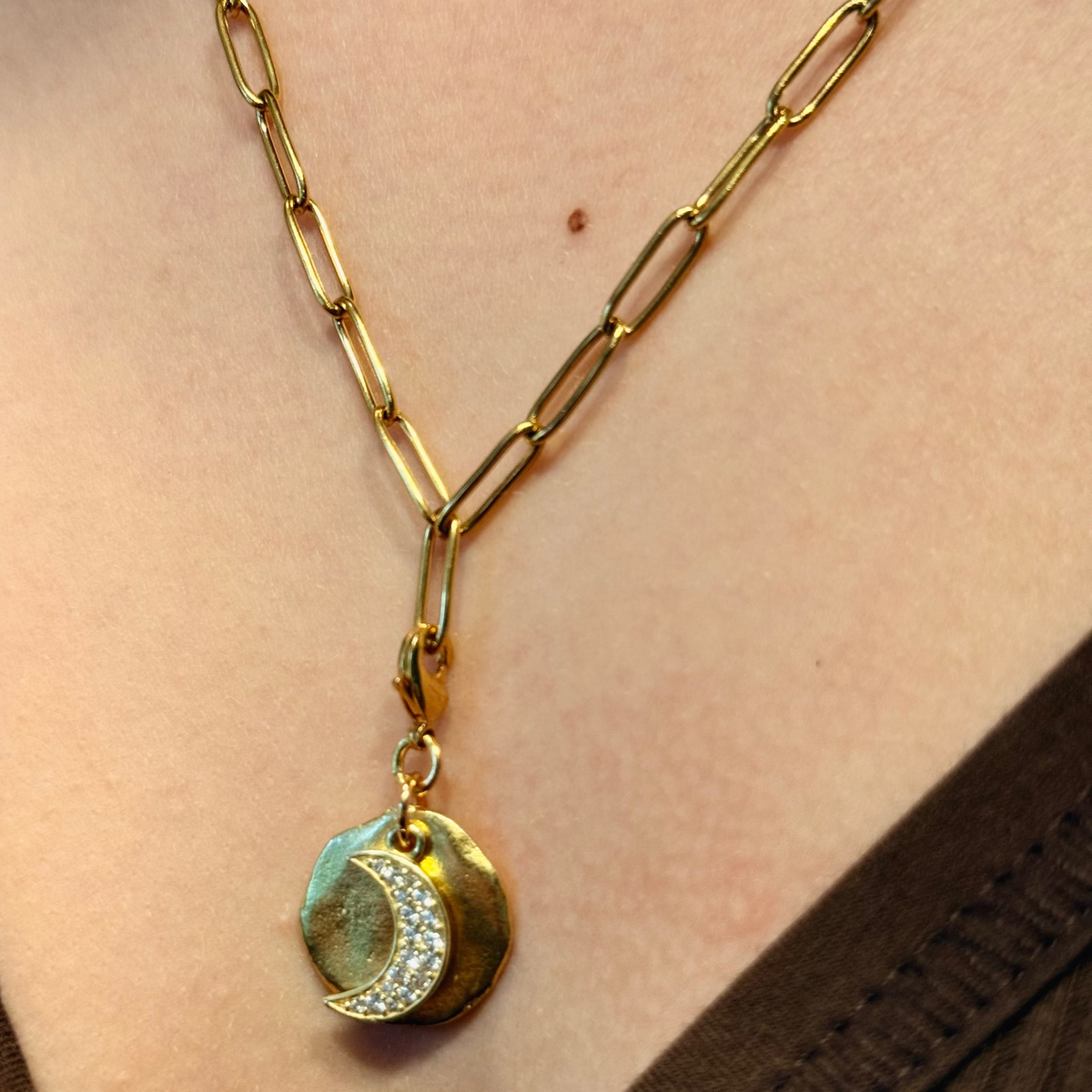 Gold necklace with a pendant worn by a person