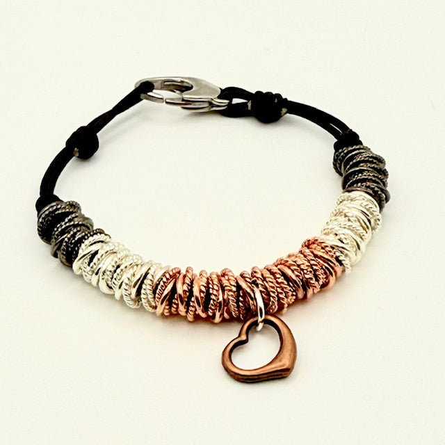 Bracelet with black cord, metallic beads, and heart charm on a white background