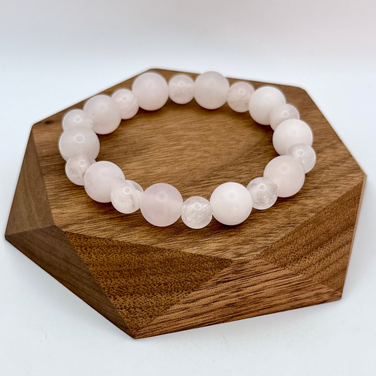 Studio photo of a flat laid Amelie Rose Quartz Bracelet featuring alternating larger matte and smaller polished pale pink rose quartz beads.