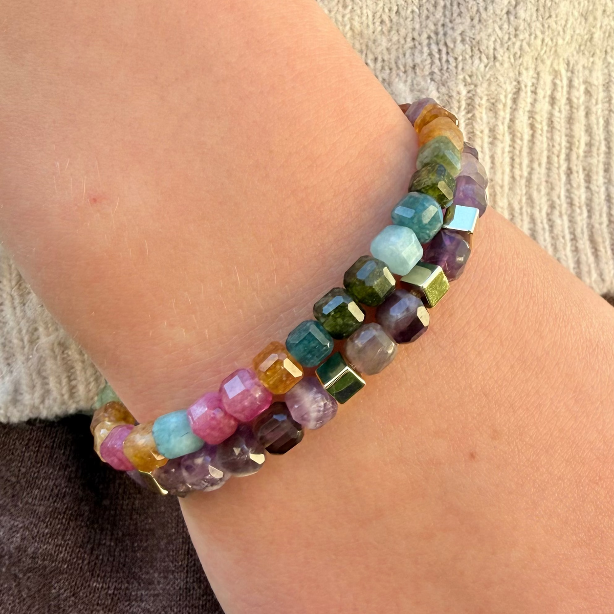 Multicolored beaded bracelet on a wrist with a neutral background