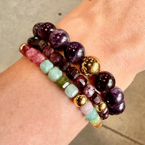 Stack of colorful beaded bracelets on a wrist with a neutral background