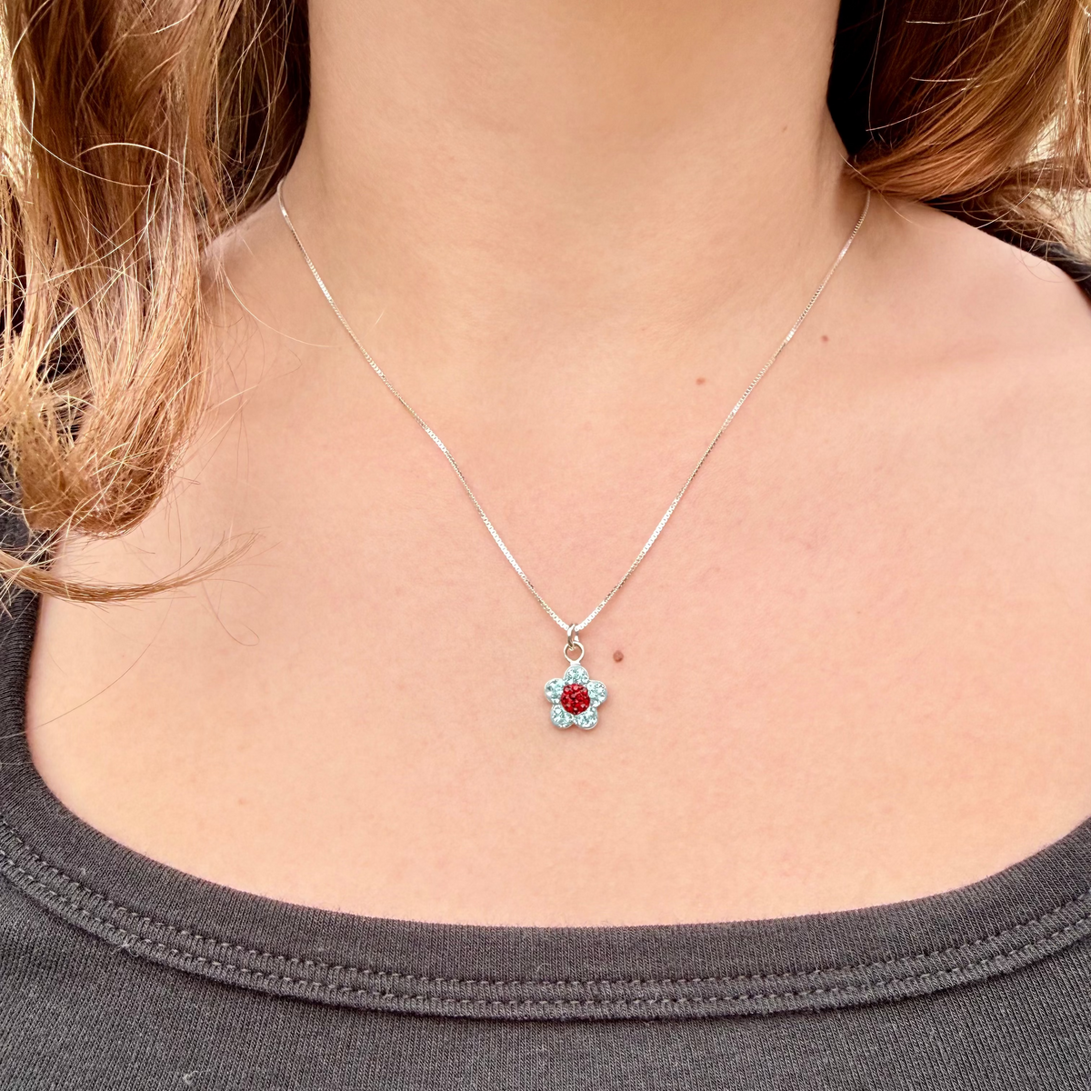 Necklace with a flower-shaped pendant worn by a person