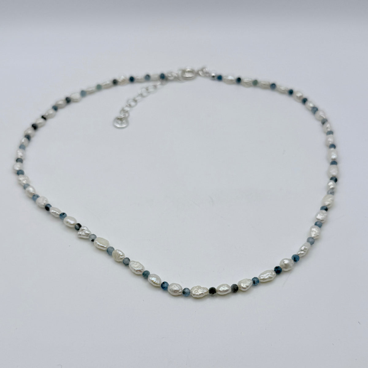 Pearl necklace with blue and black beads on a white background