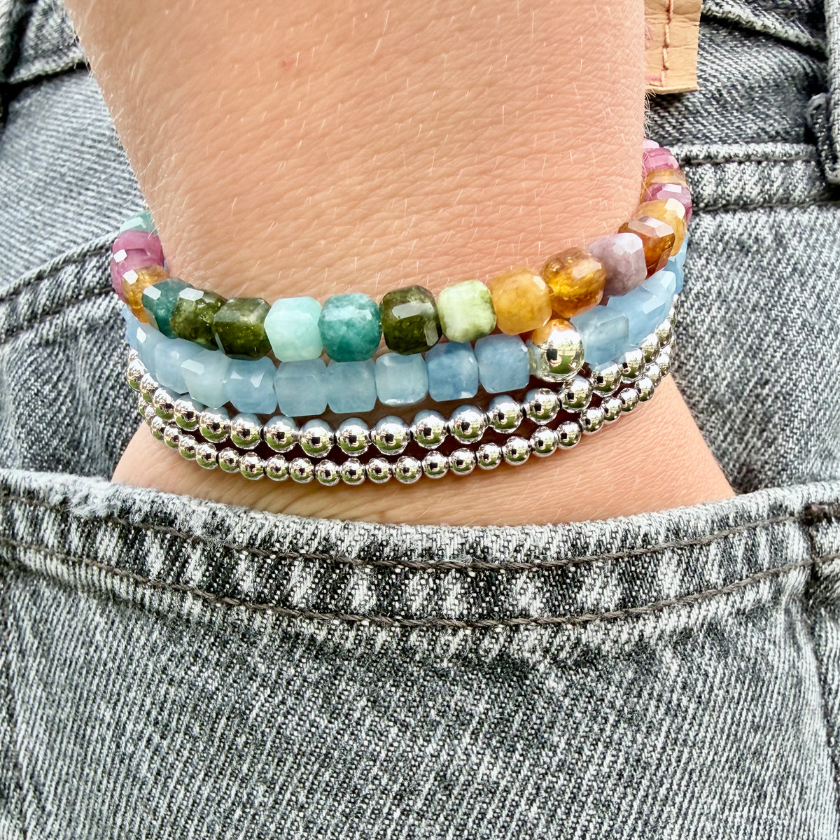 5mm faceted Aquamarine cube bracelet with sterling silver accent stacked with 3&4mm sterling silver stretch-to-fit bracelets and 5mm faceted cube Tourmaline bracelet – March birthstone stretch bracelet handmade in California
