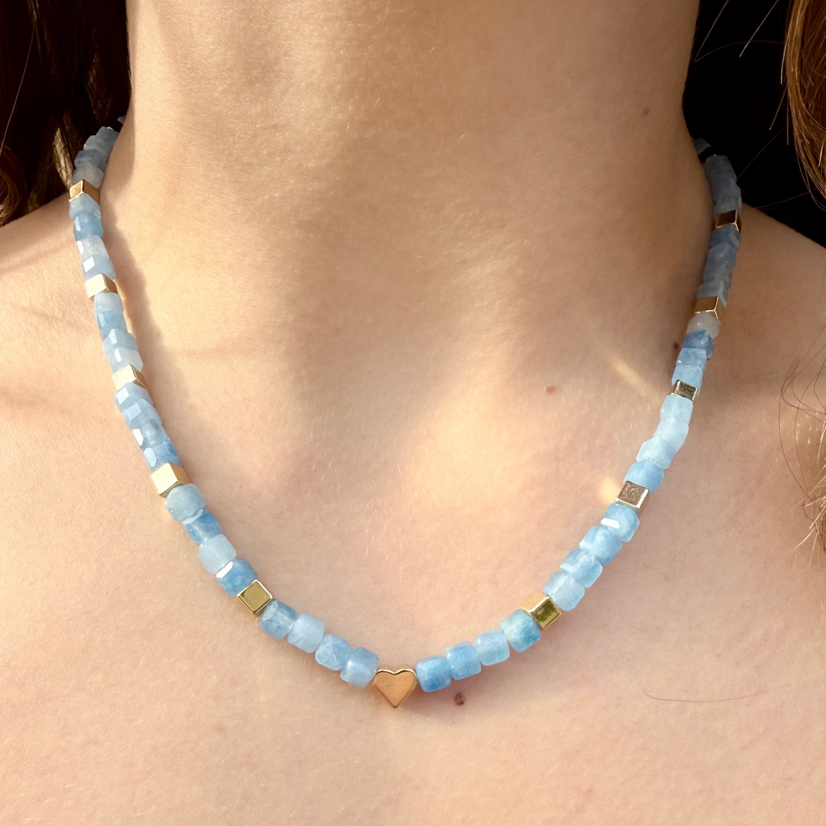 Necklace with blue beads and gold accents on a person's neck