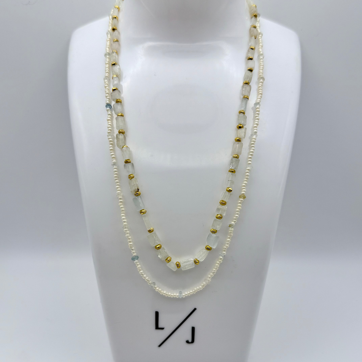 Two-layered beaded necklace on a white bust with 'LJ' branding.