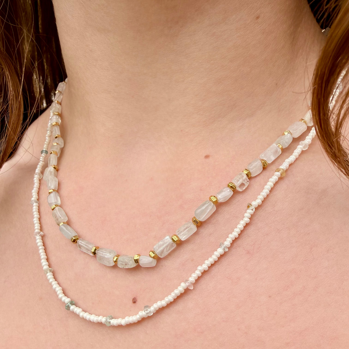 Two pearl necklaces with gold accents on a person's neck
