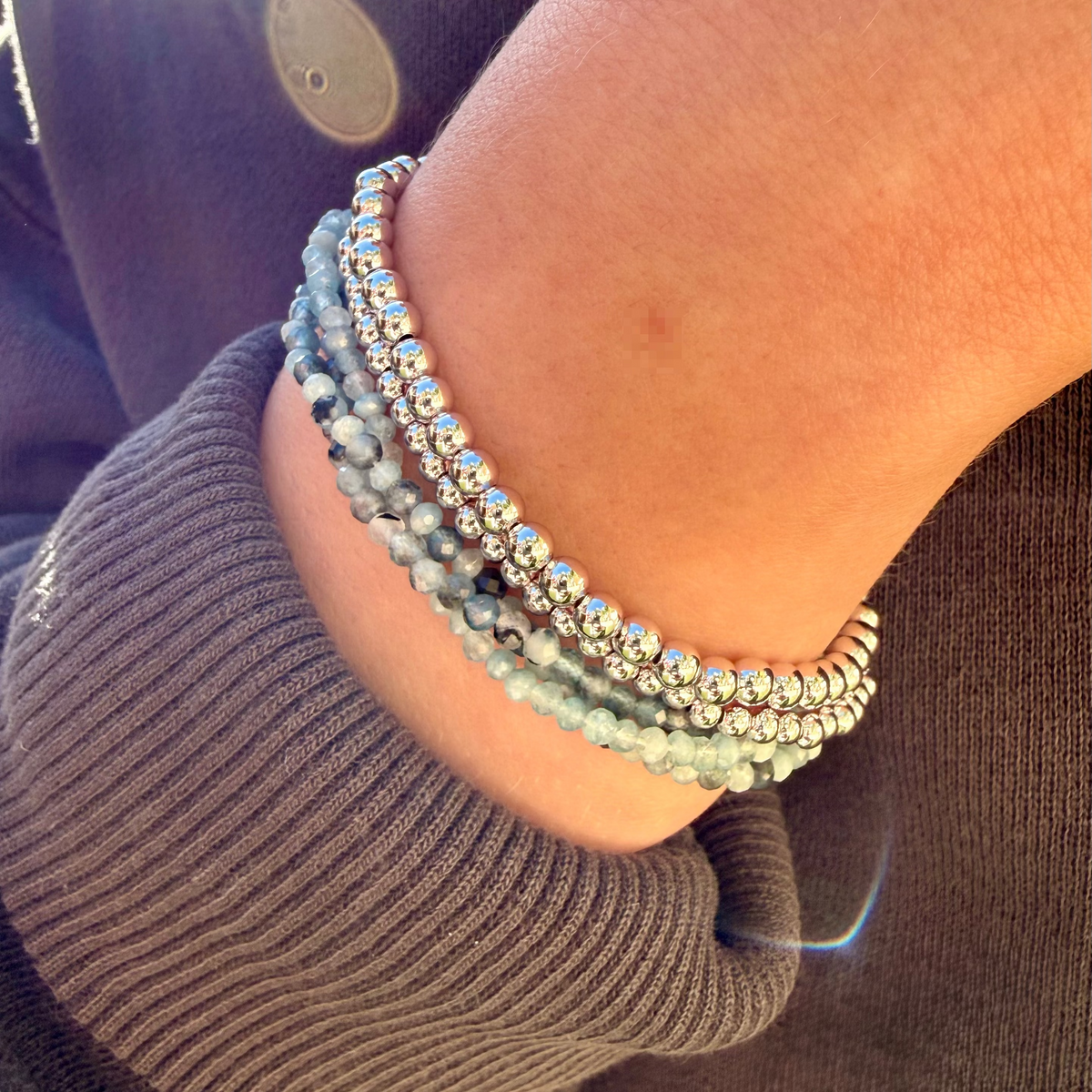 Close-up of a wrist wearing multiple beaded bracelets with a blurred background