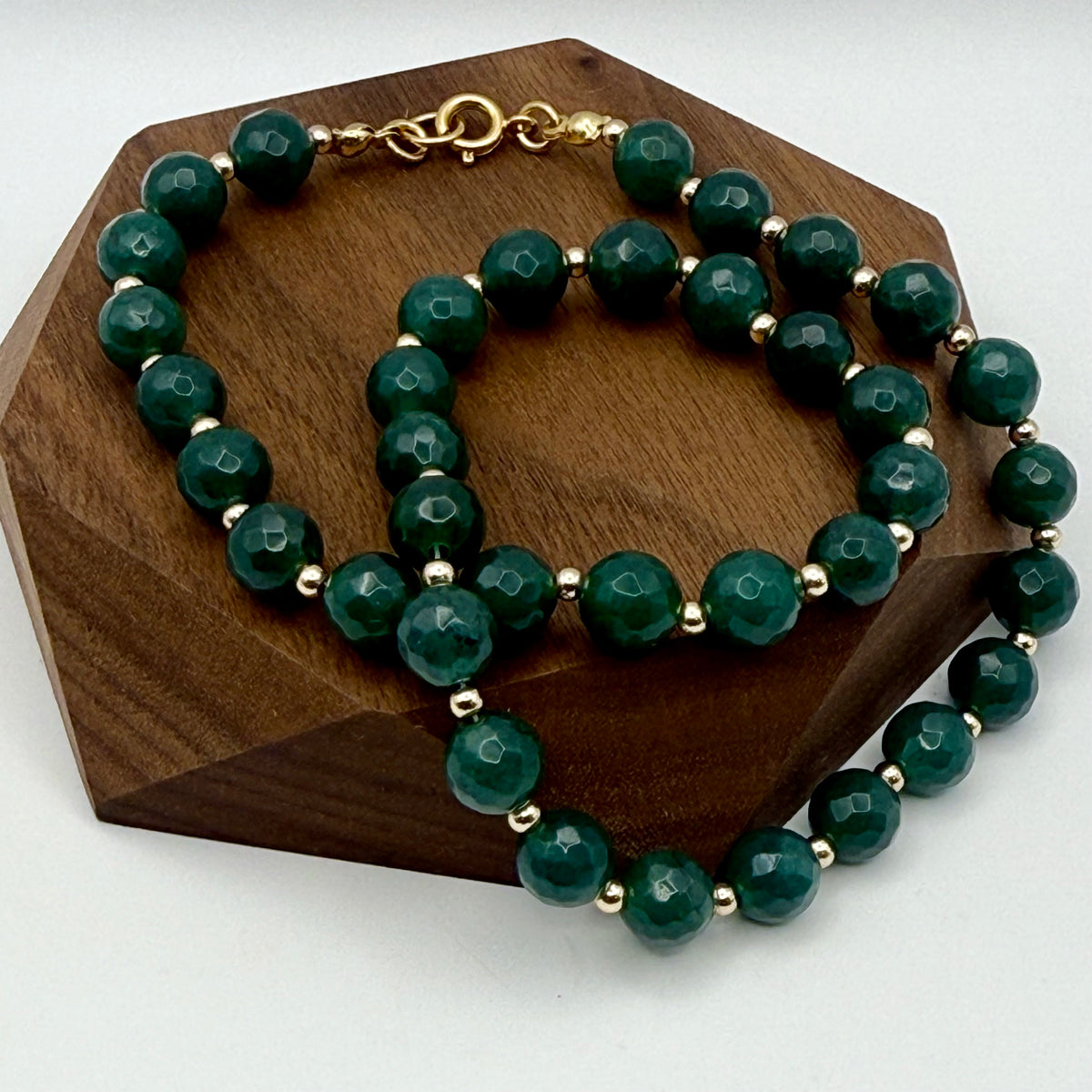 Dark emerald green jade large round beaded necklace with tiny gold bead accents on display