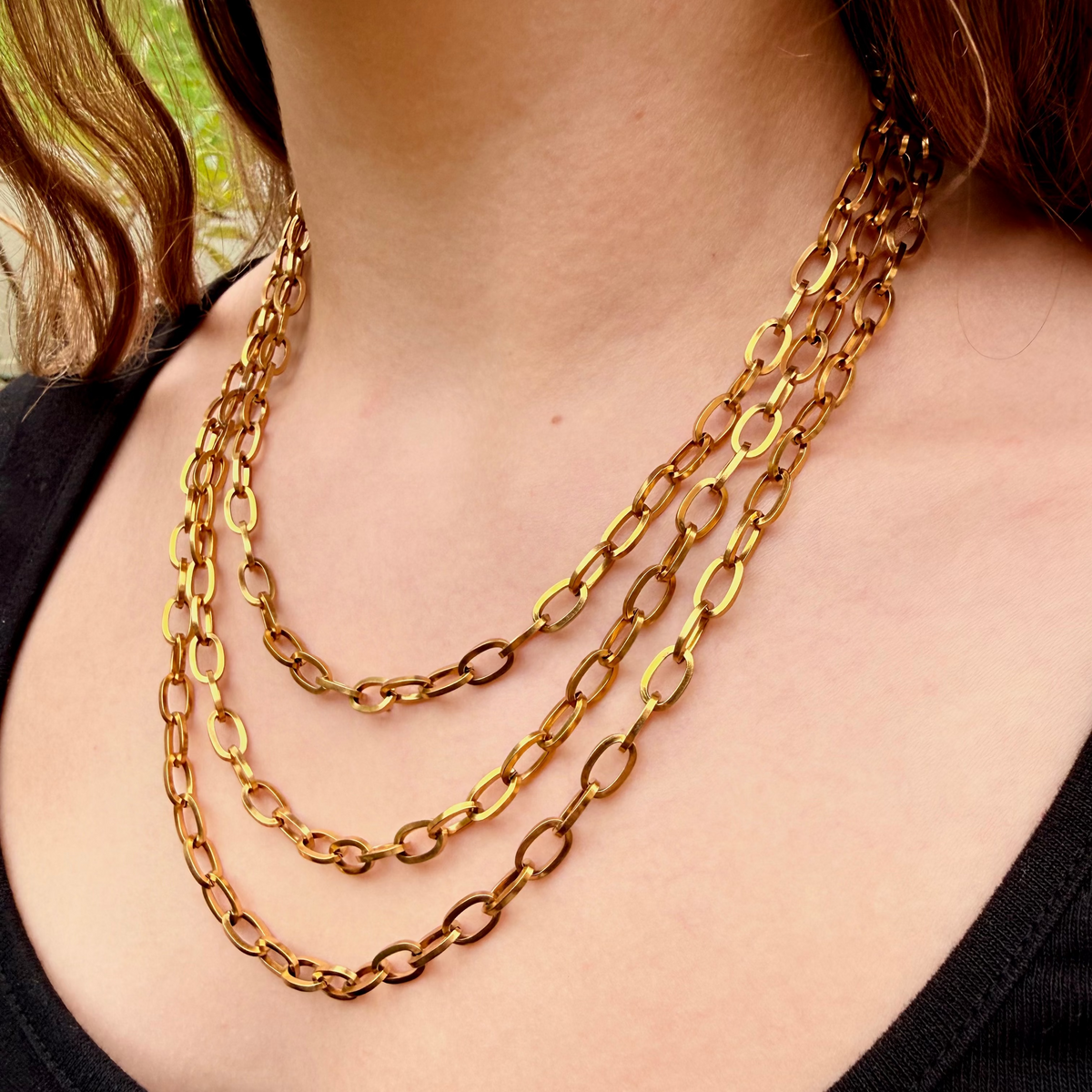Gold chain necklace on a person wearing a black top