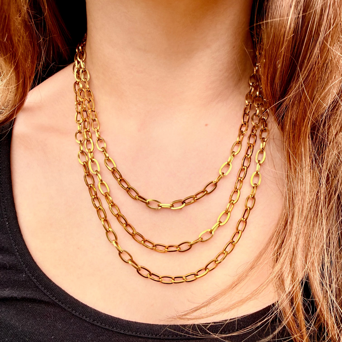 Gold chain necklace on a person wearing a black top
