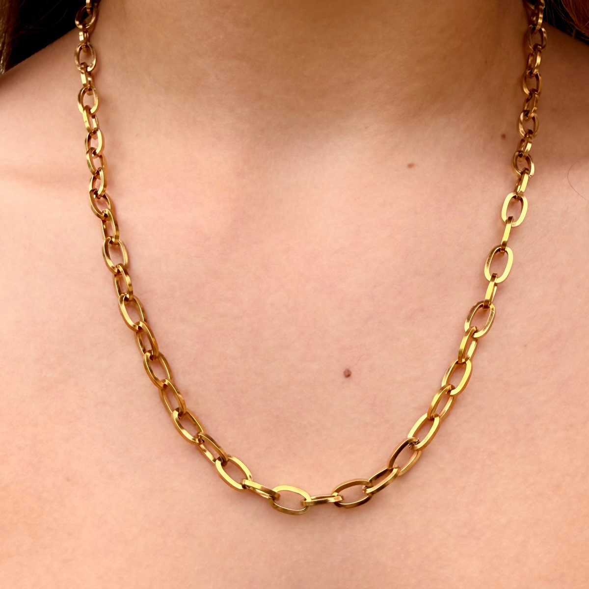 Gold chain necklace on a person wearing a light green top.