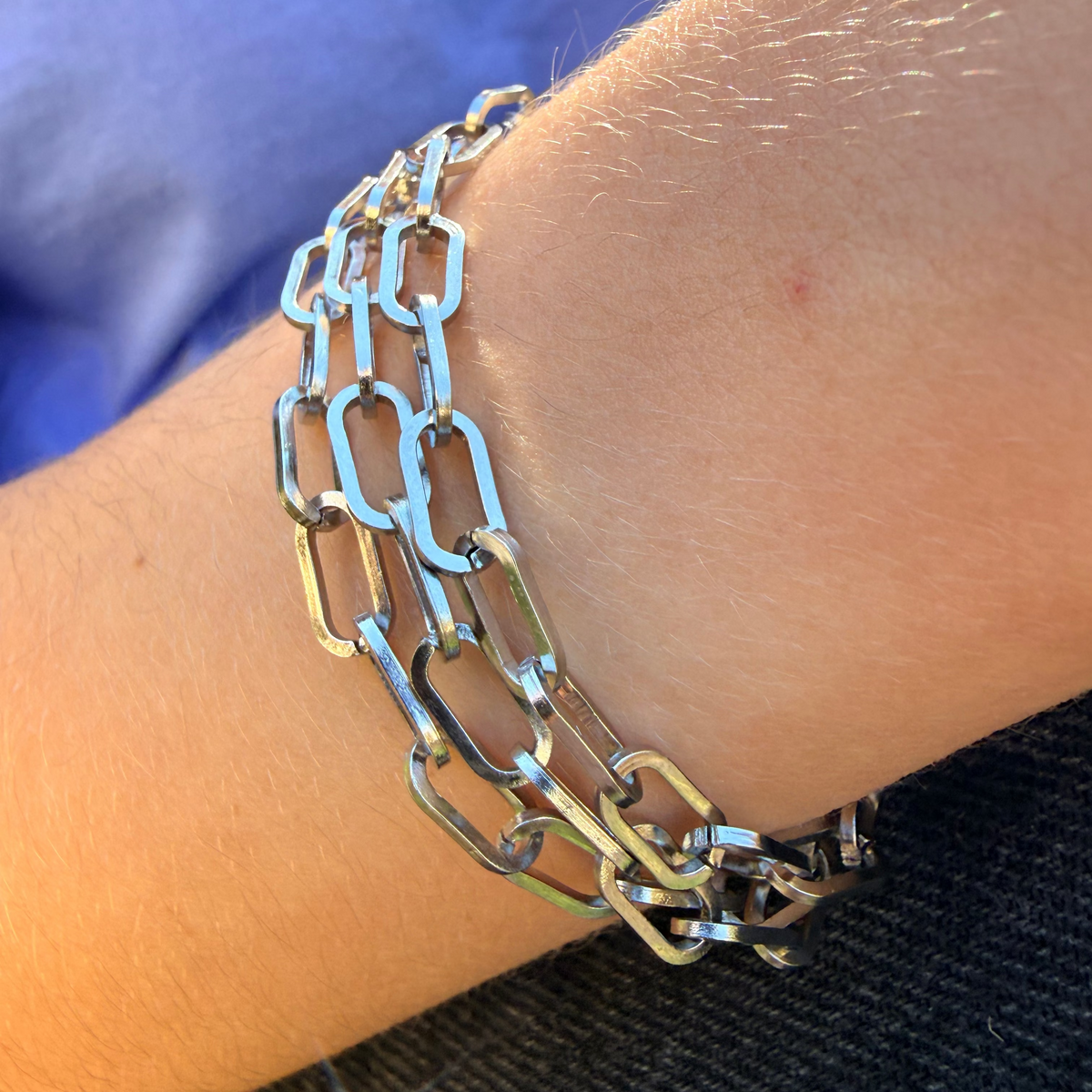 Close-up of a person's wrist wearing a silver chain bracelet.