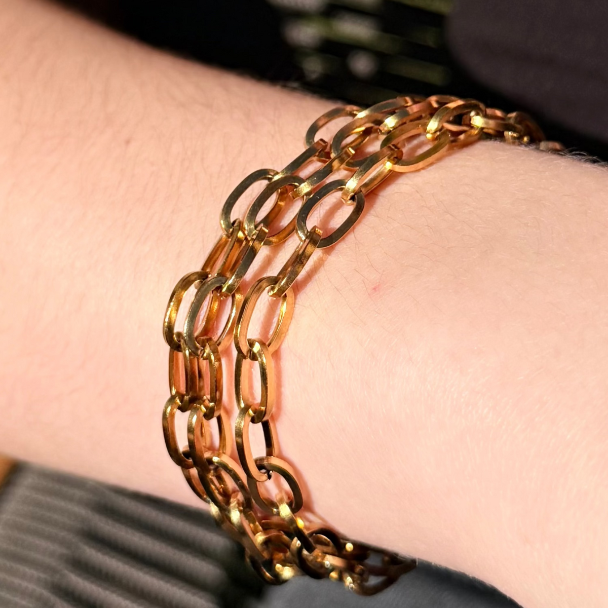 Gold chain bracelet on a wrist with a blurred background