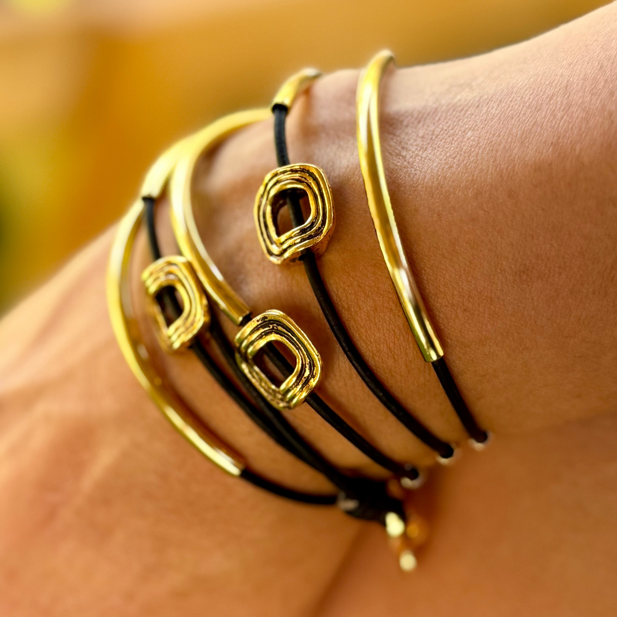 Gold and black bracelets on a wrist with a blurred background