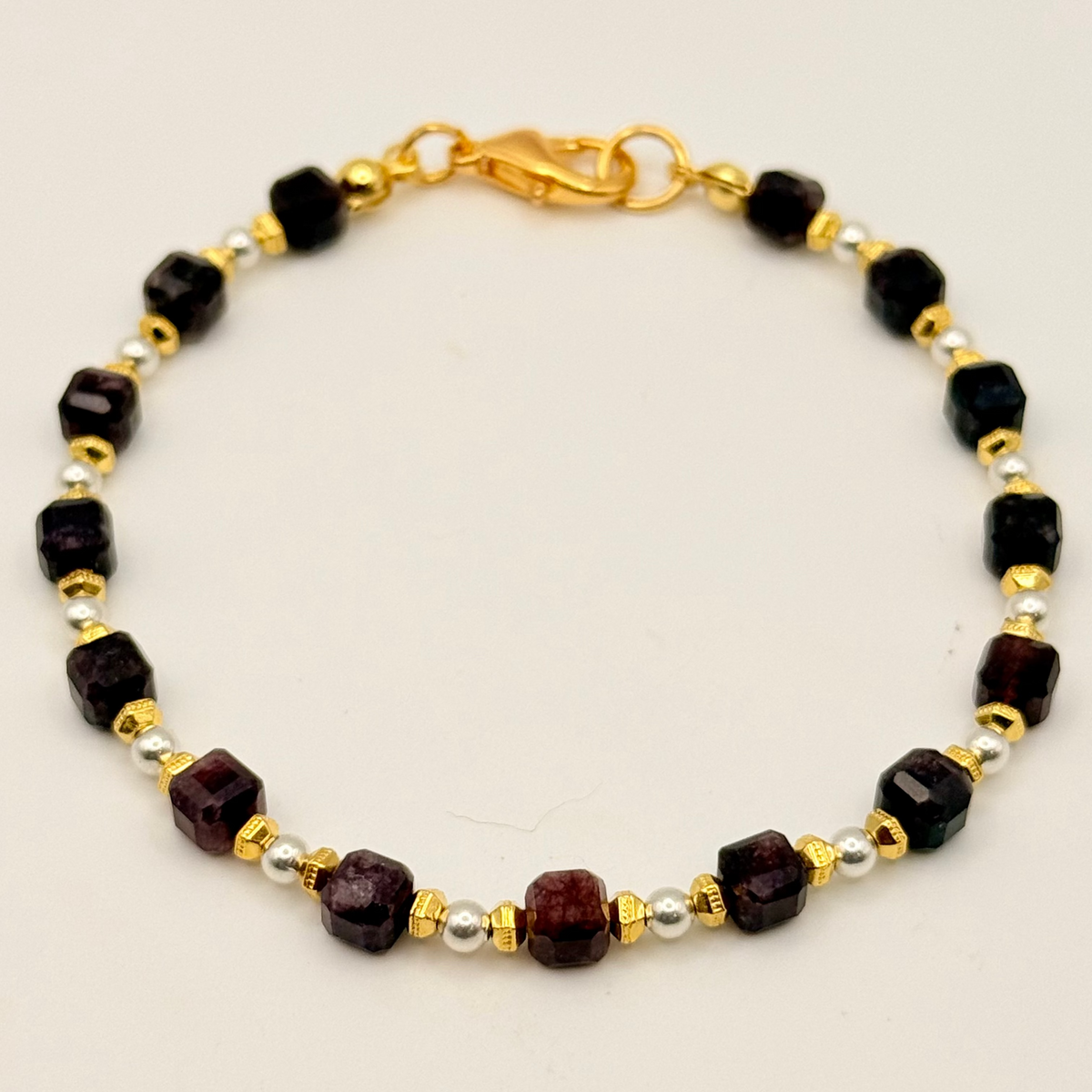 Bracelet with black, gold, and silver beads on a beige background