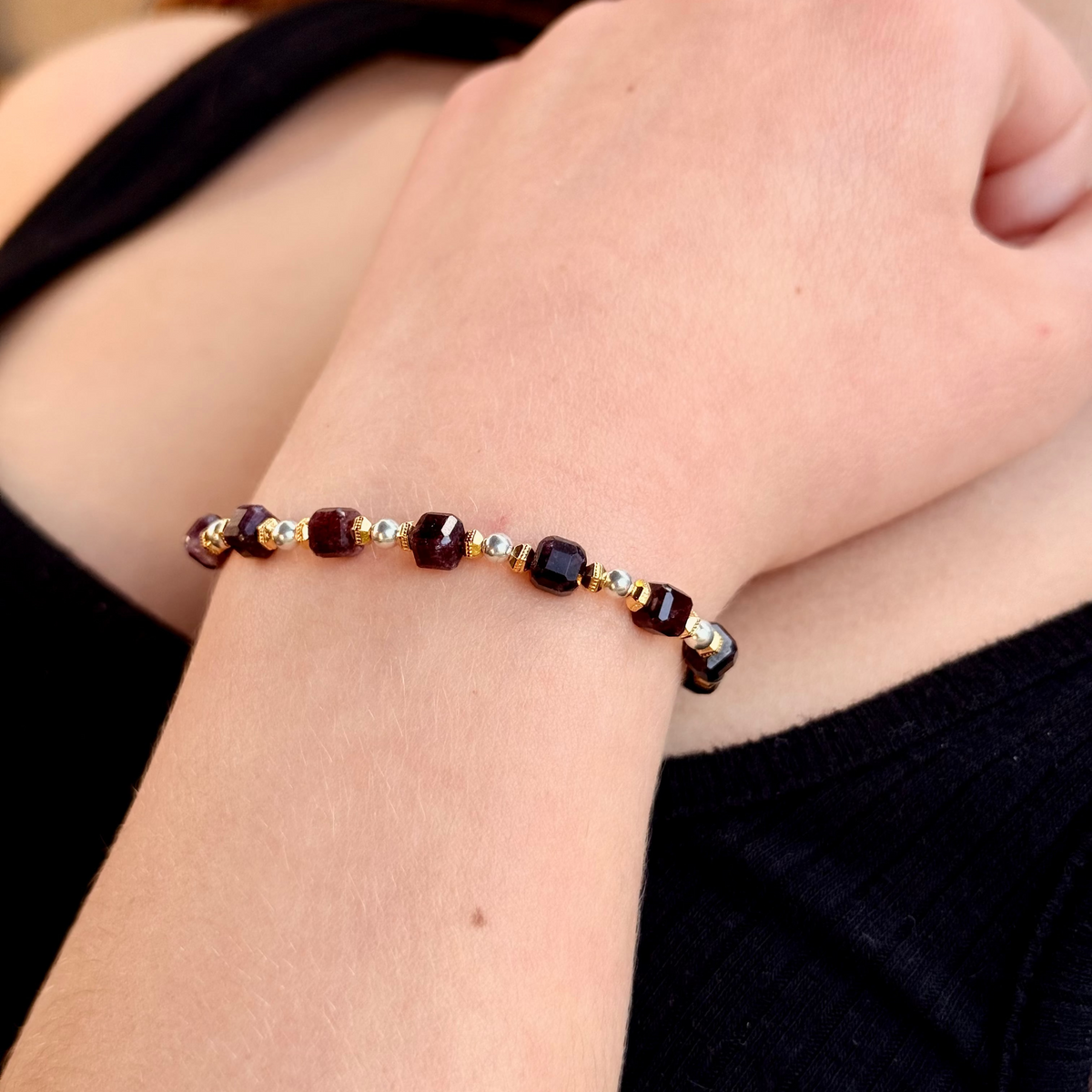 Close-up of a wrist wearing a beaded bracelet with a blurred background