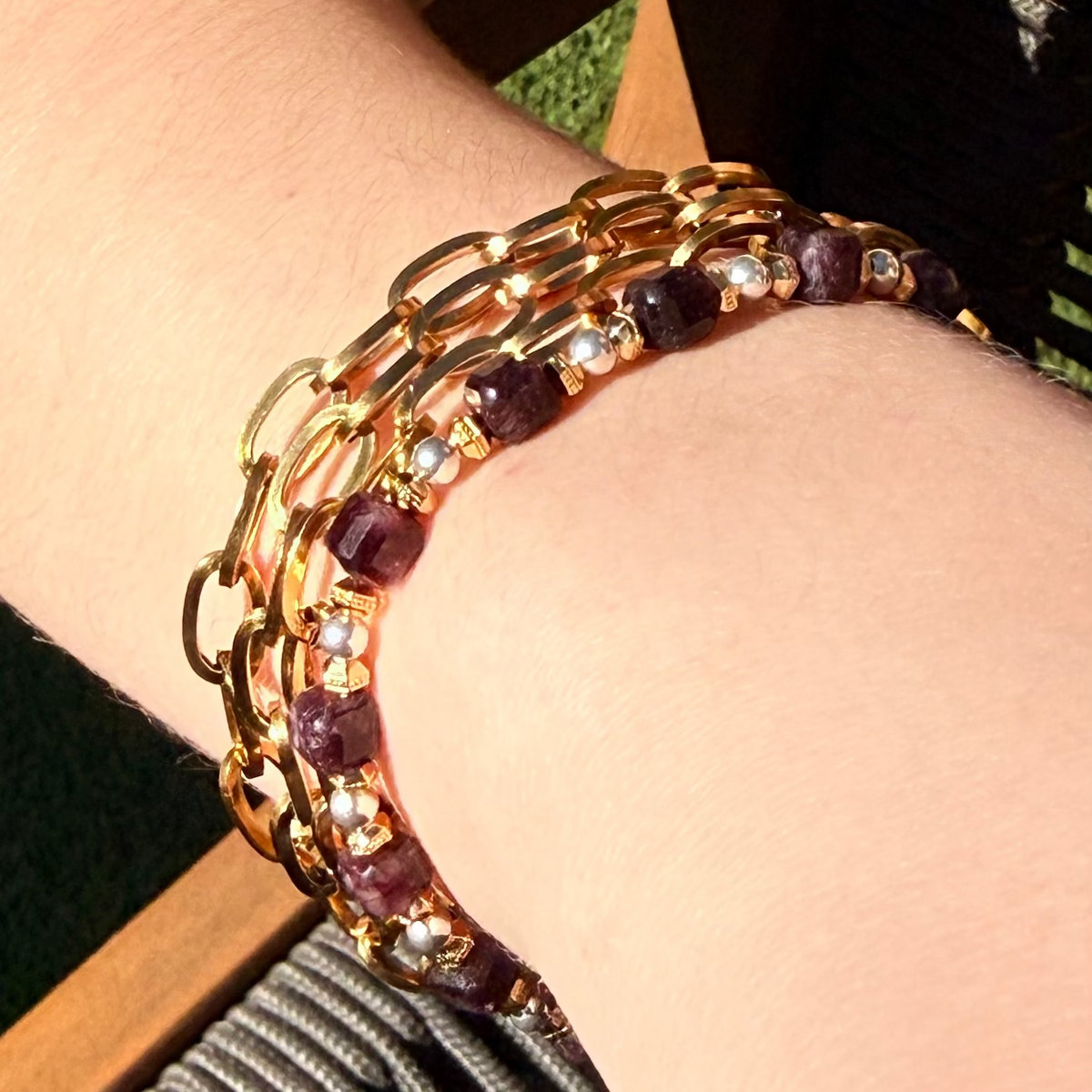 Gold and red beaded bracelet on a wrist with a blurred background