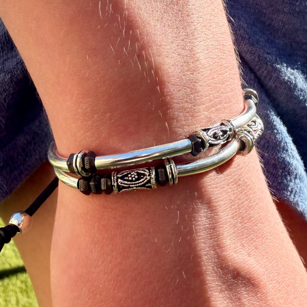 Close-up of a wrist wearing a silver bracelet with intricate designs.