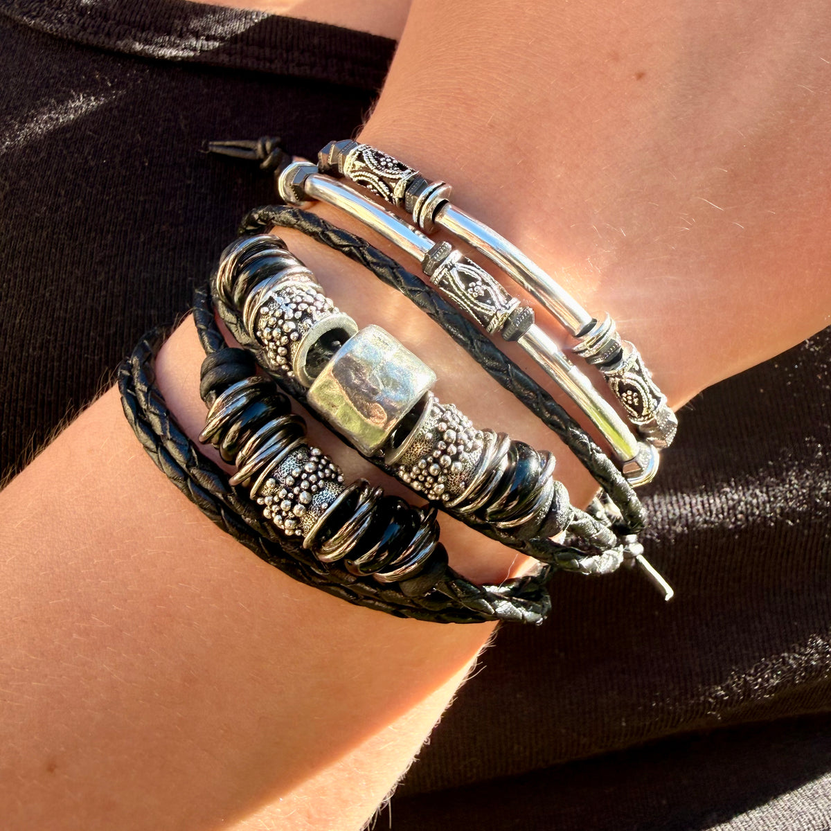 Close-up of a wrist wearing multiple leather and metal bracelets.