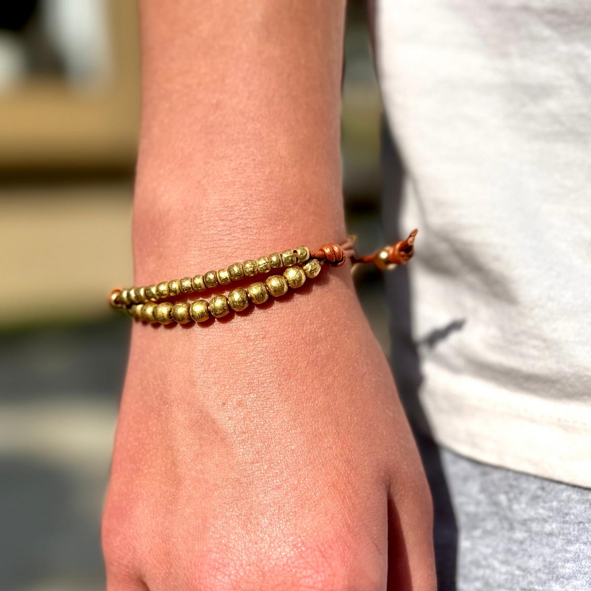 Gold beaded bracelet on a wrist with a blurred background