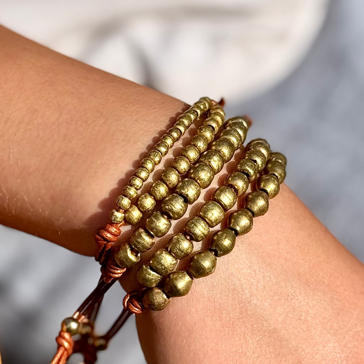 Gold beaded bracelets on a wrist with a blurred background