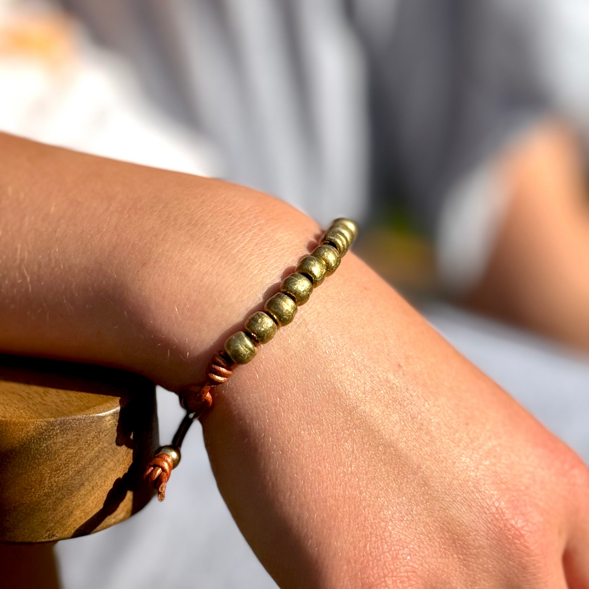 Close-up of a wrist wearing a beaded bracelet with a blurred background