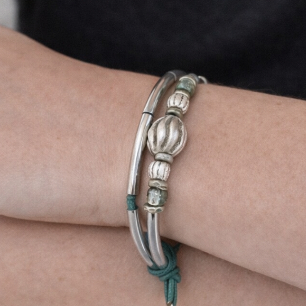 Silver bracelet on a person's wrist with a plain background