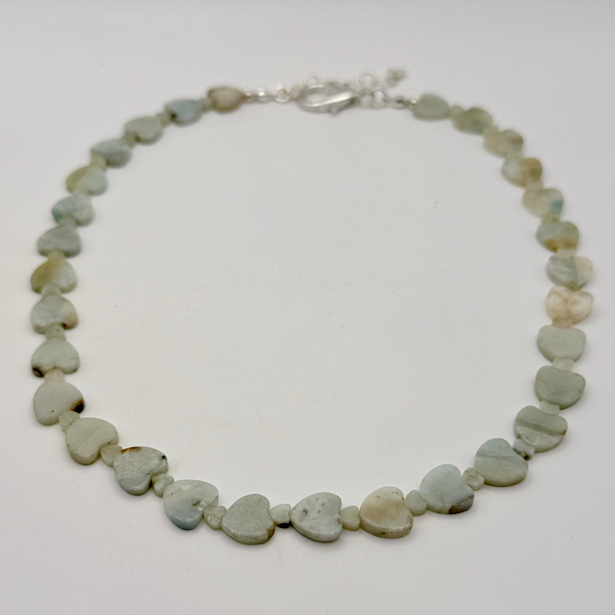 Adjustable 16 to 18 inch necklace with a mix of large and small light teal Amazonite heart-shaped gemstones and a silver clasp.