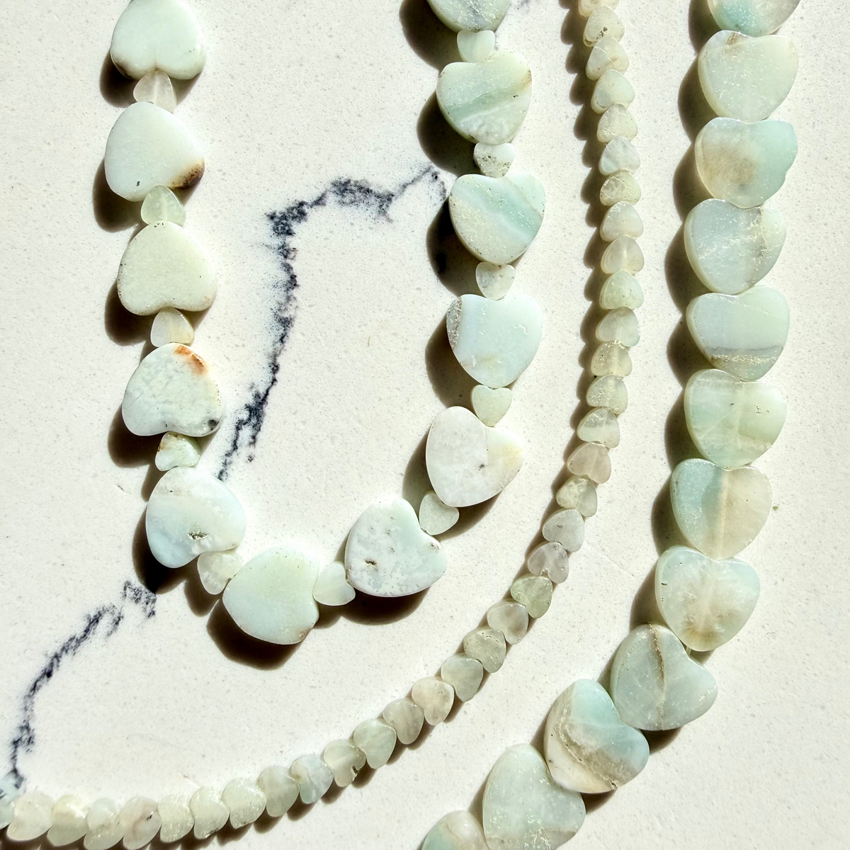 Close-up of a necklace with light green beads on a marble surface