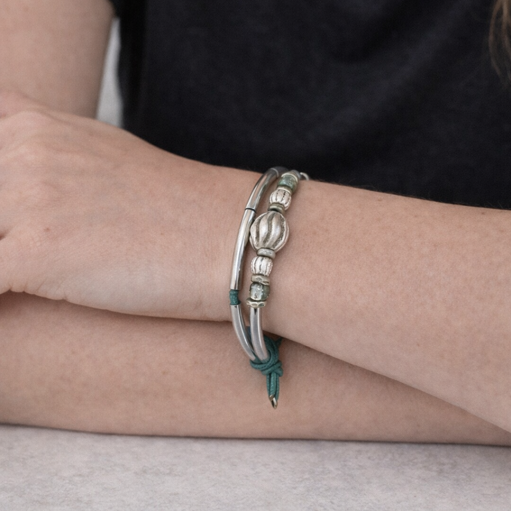 Silver bracelet on a person's wrist with a plain background