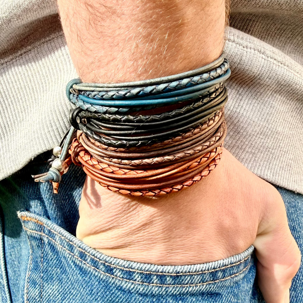 Multiple leather bracelets on a wrist with a neutral background