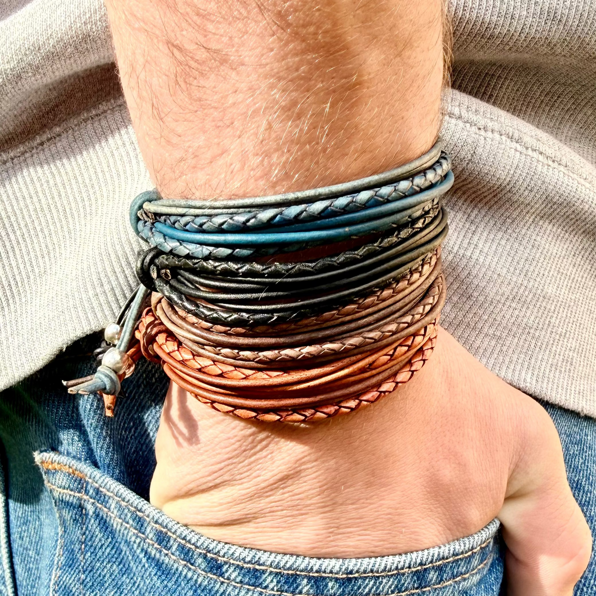 Multiple leather bracelets on a wrist with a neutral background