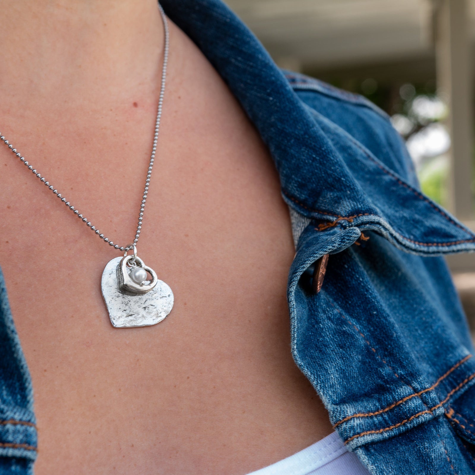 Necklace with a heart-shaped pendant worn by a person in a black top.