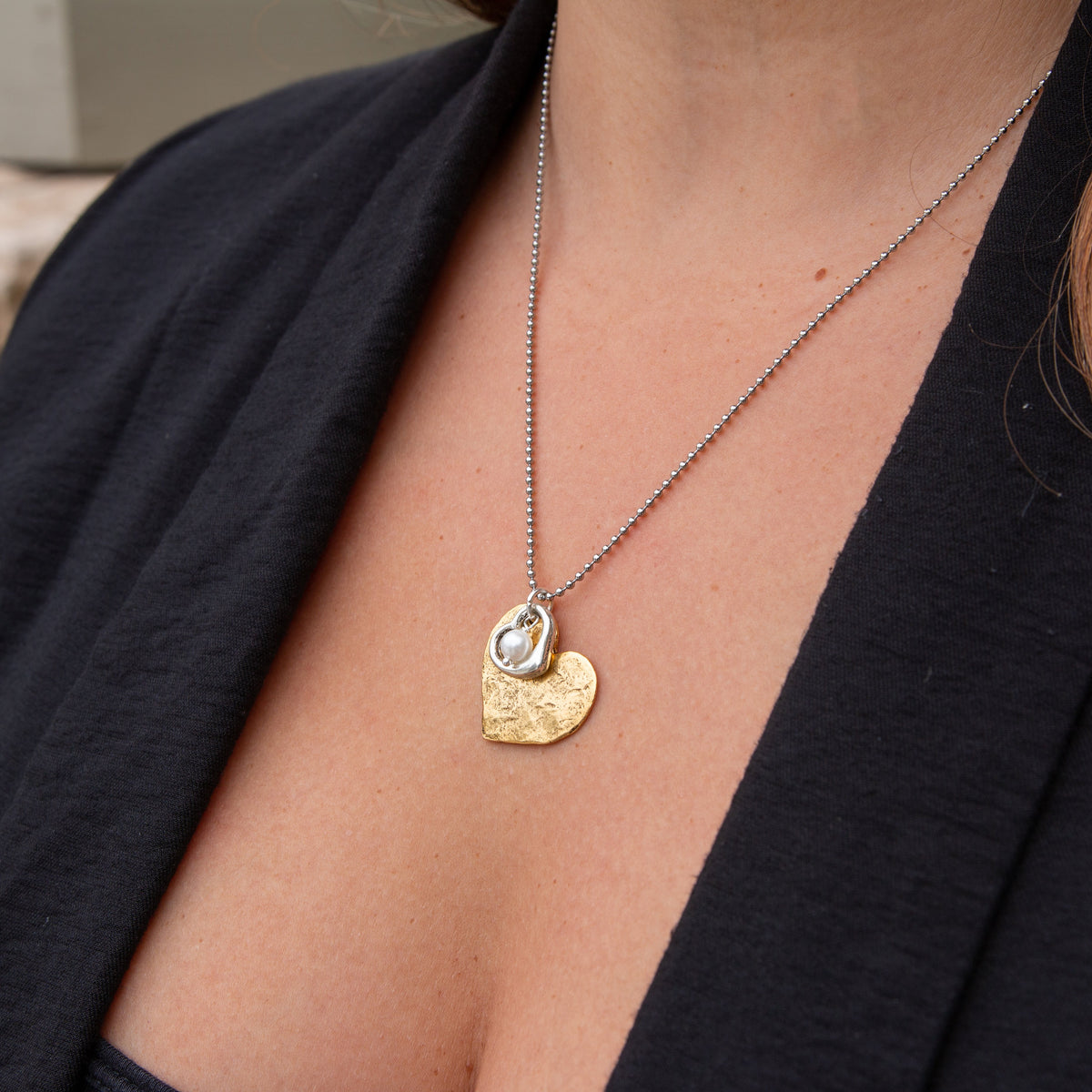 Necklace with a heart-shaped pendant worn by a person in a black top.