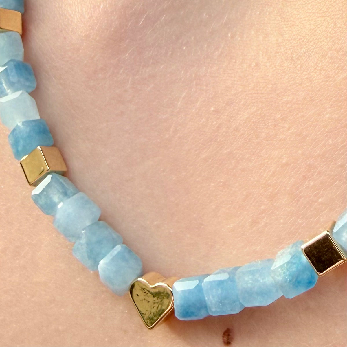 Close-up of 5mm faceted natural Aquamarine cube beads with gold-plated accent cubes