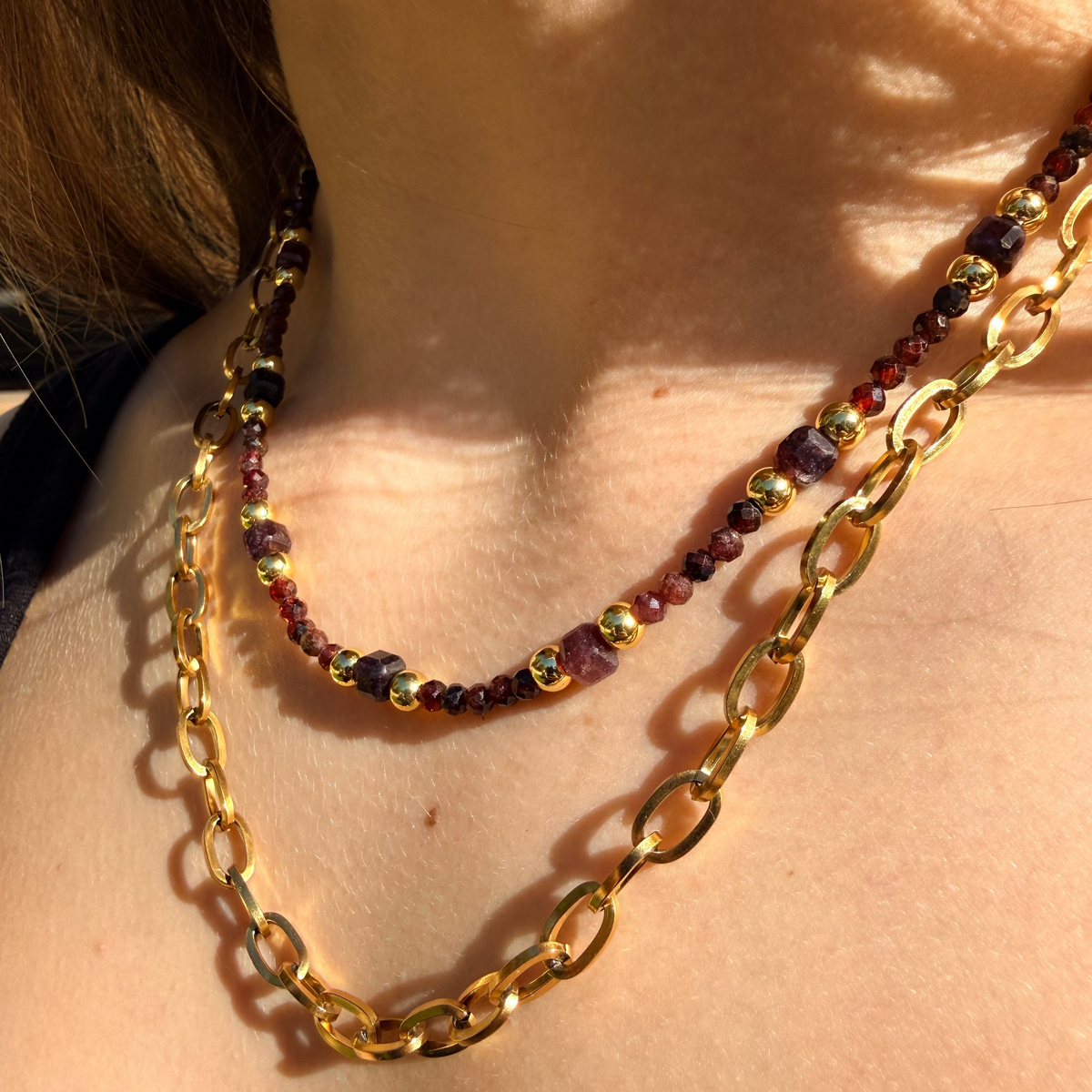 Garnet and gold chunky chain necklace on a womans neck.