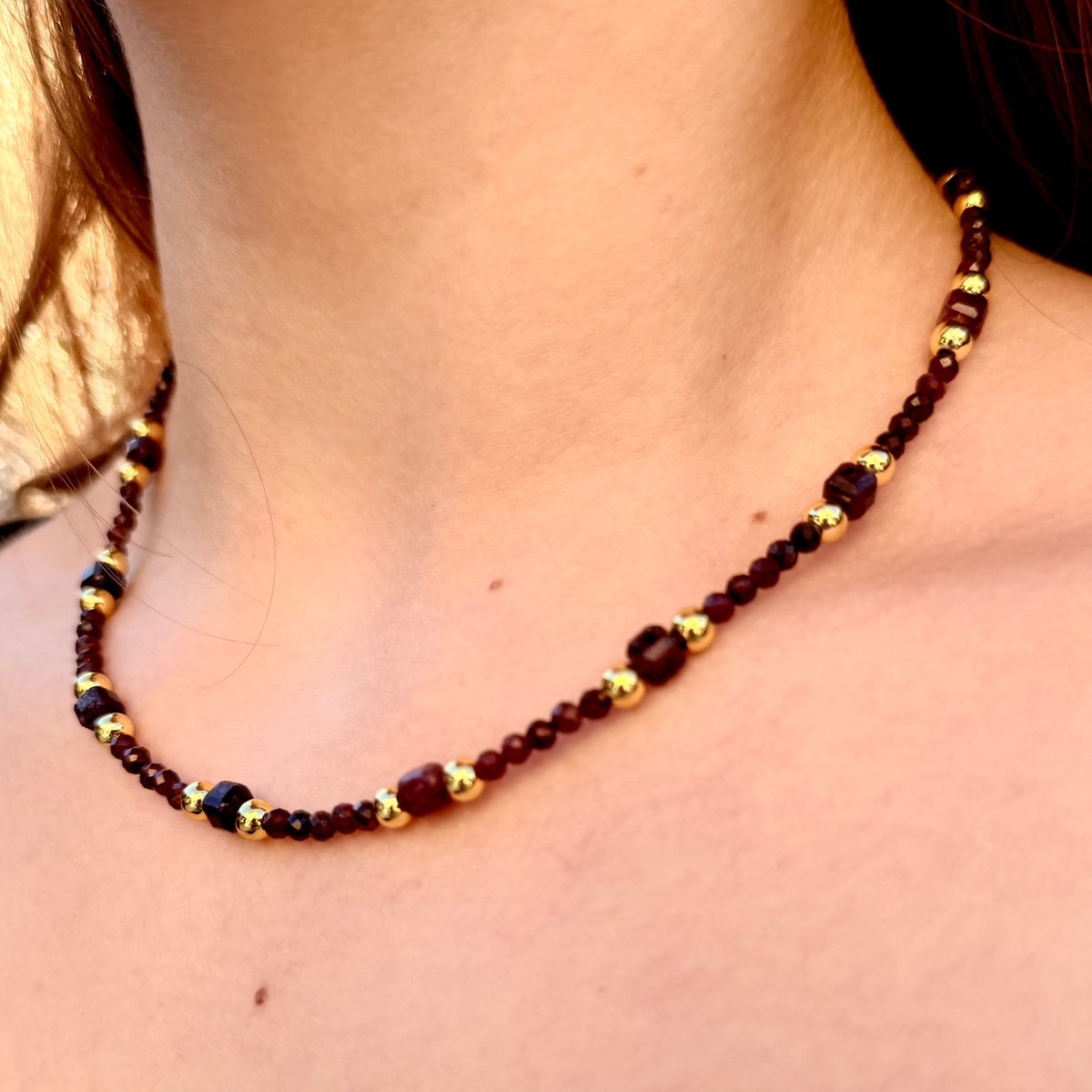 Close-up of a person wearing a beaded necklace with a blurred background