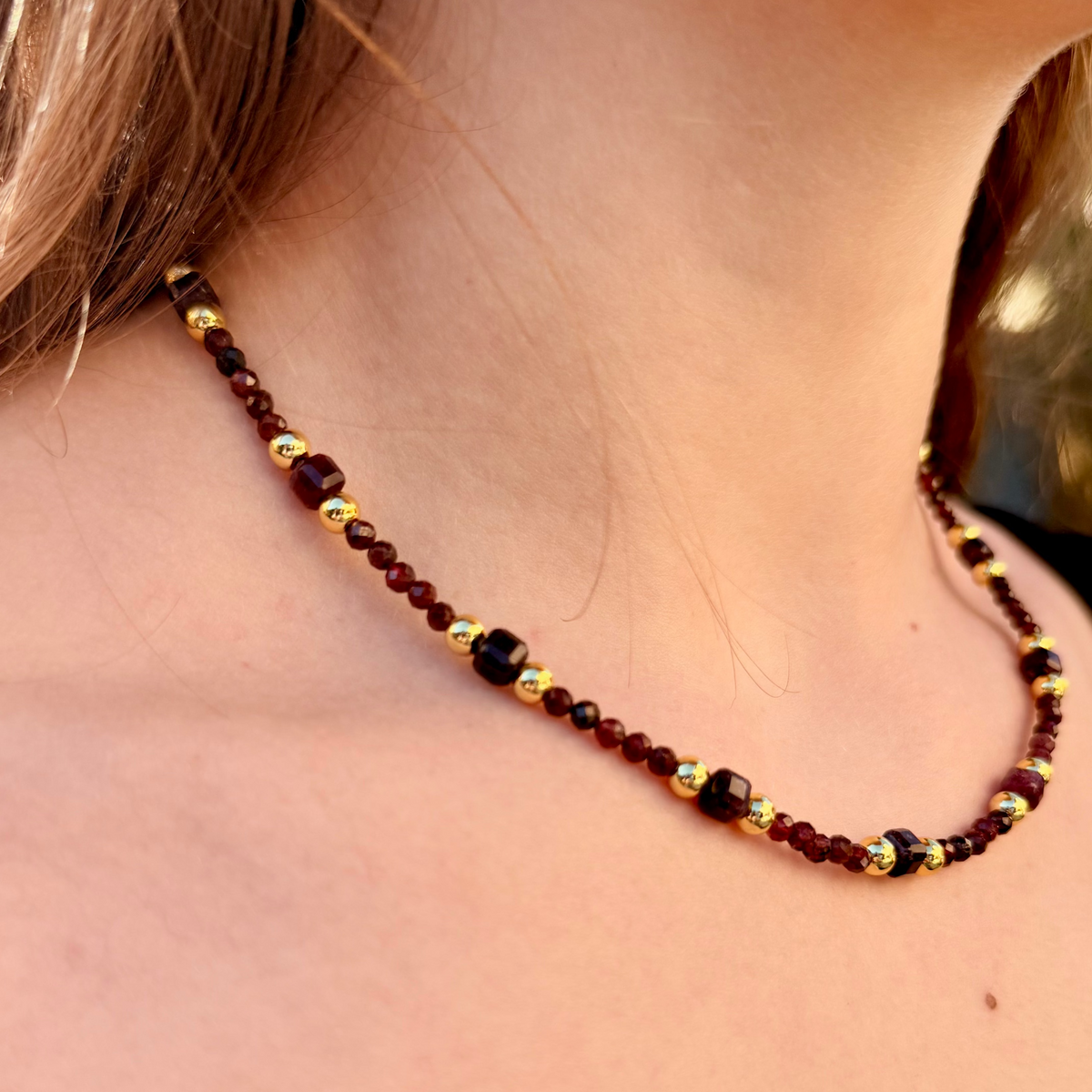 Beaded necklace on a person with a blurred natural background