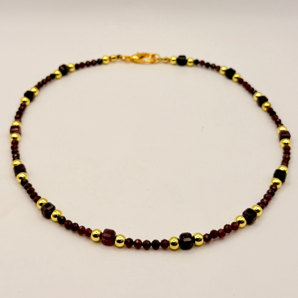 Necklace with alternating brown and gold beads on a beige background