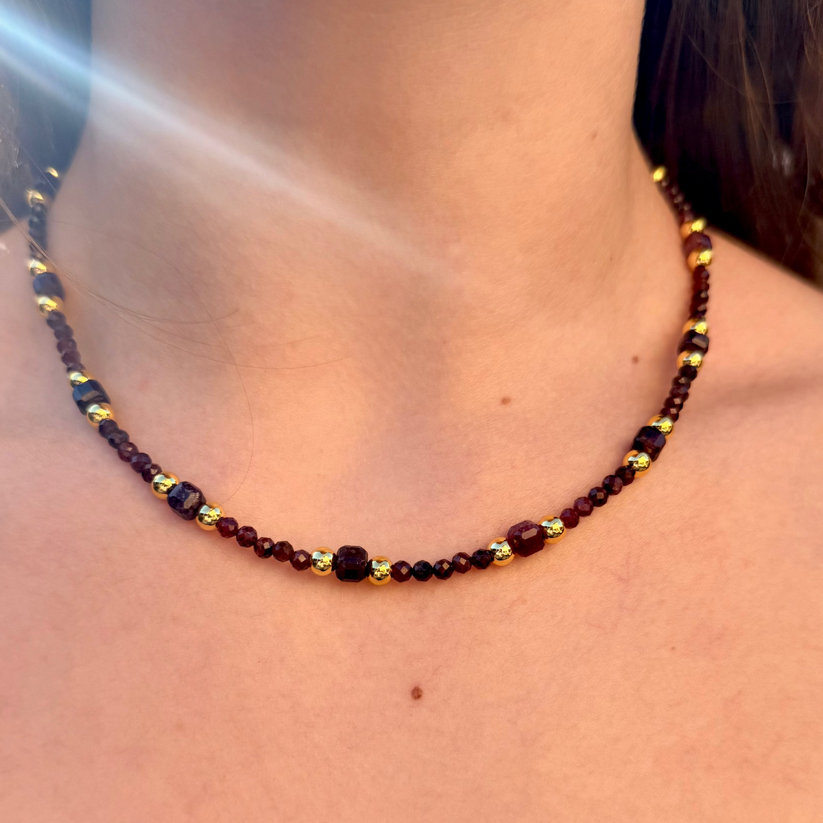 Necklace with red and gold beads on a person's neck
