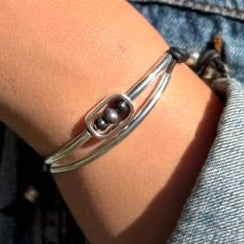 Silver bracelet with a central bead on a wrist against a denim background