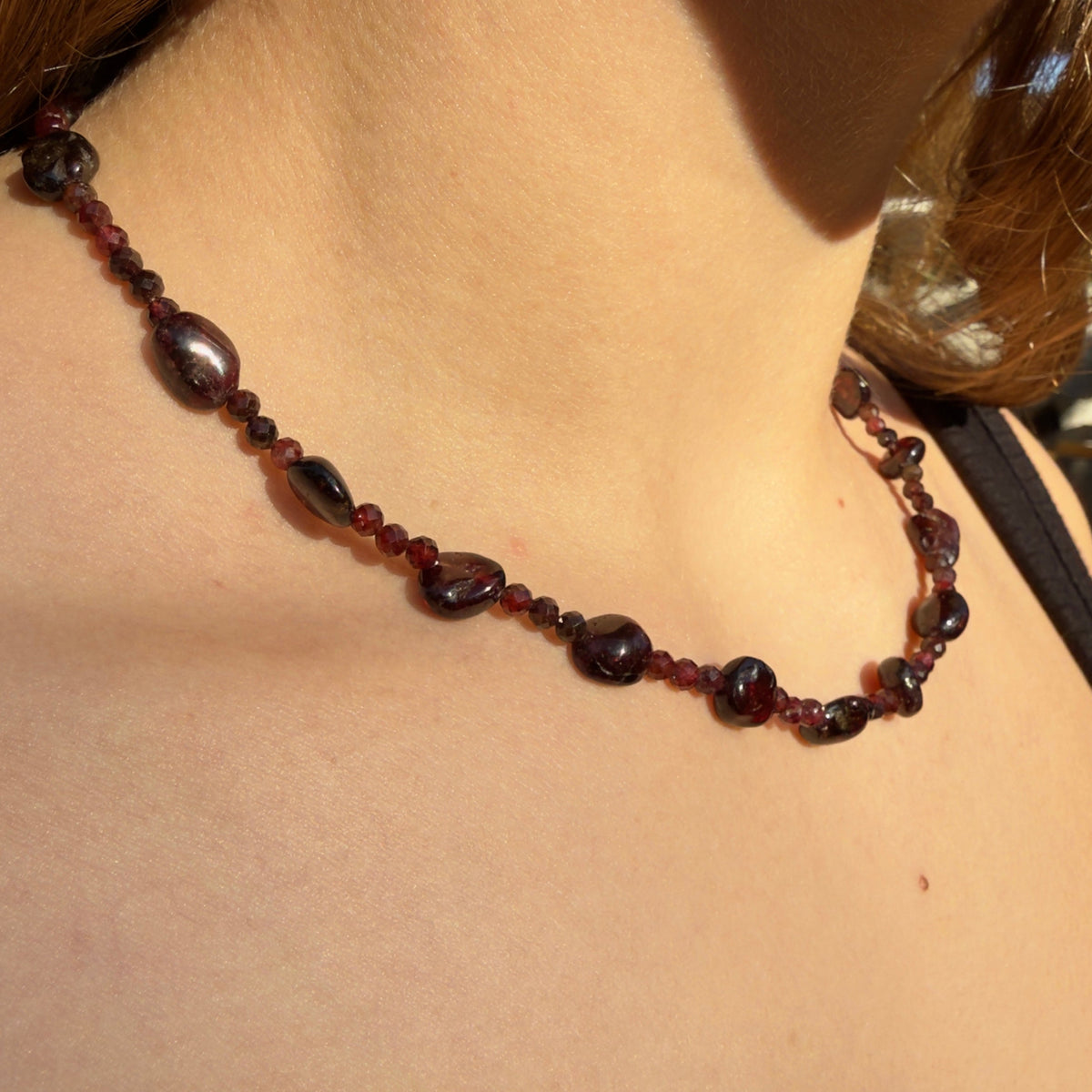 Necklace with red beads on a person wearing a black top.